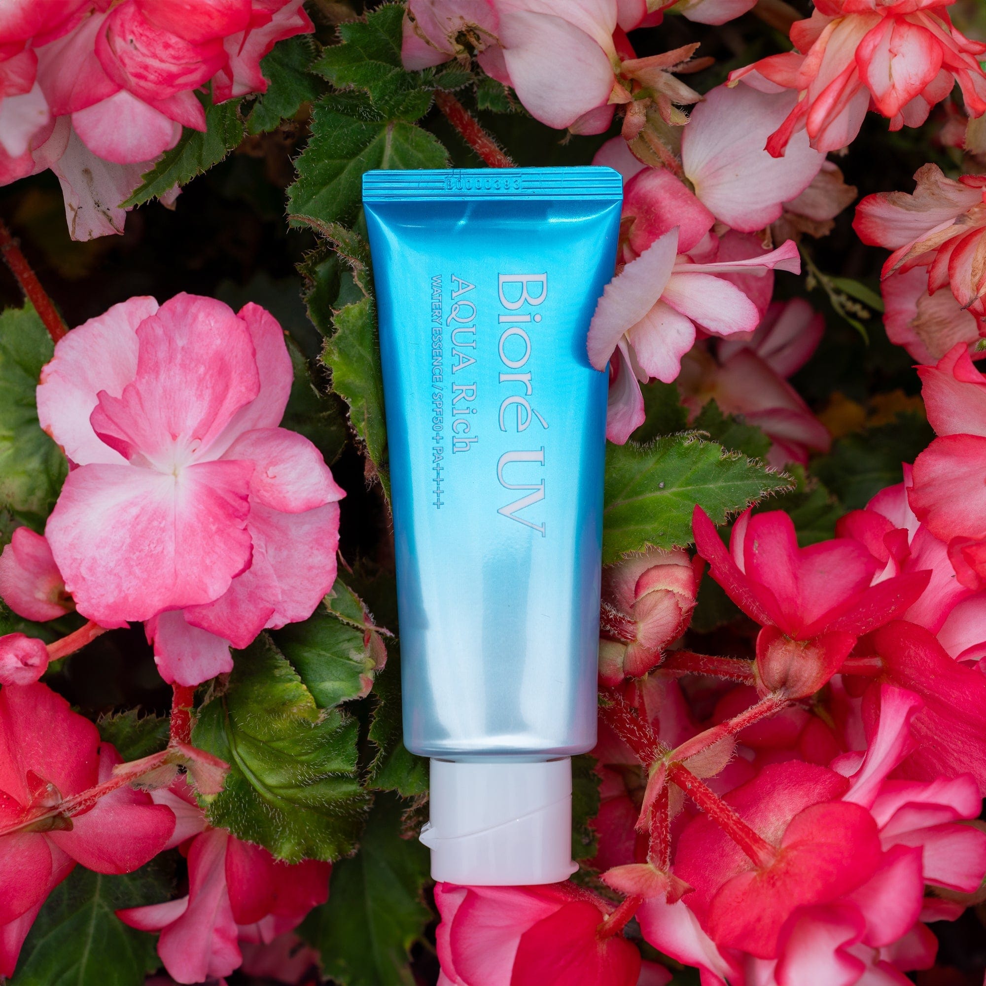 Photograph of Biore Aqua Rich Watery Essence Sunscreen SPF 50+ PA++++ in a bed of pink flowers